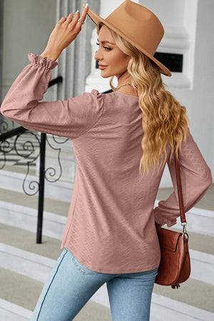 Blush pink textured puff sleeve blouse with ruffled cuffs.