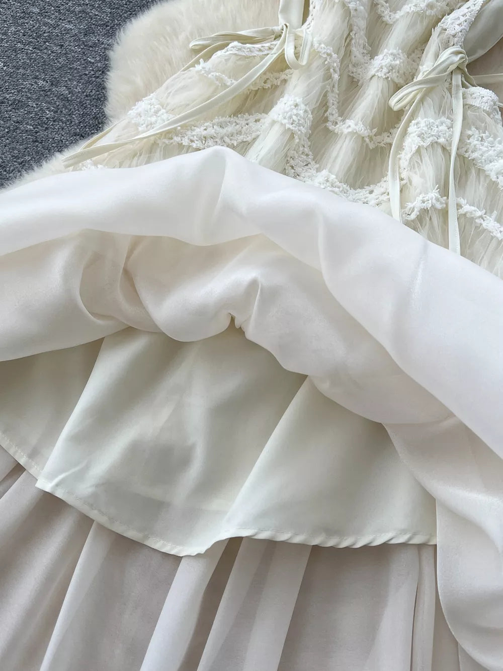 Tiered lace midi dress with bow detail, showing layered skirt and delicate fabric.