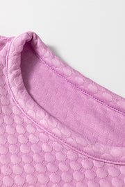 Pink purple textured quilted blouse with a round neckline and puff sleeves.
