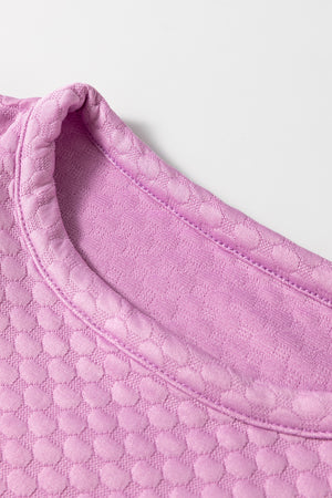 Pink purple textured quilted blouse with a round neckline and puff sleeves.