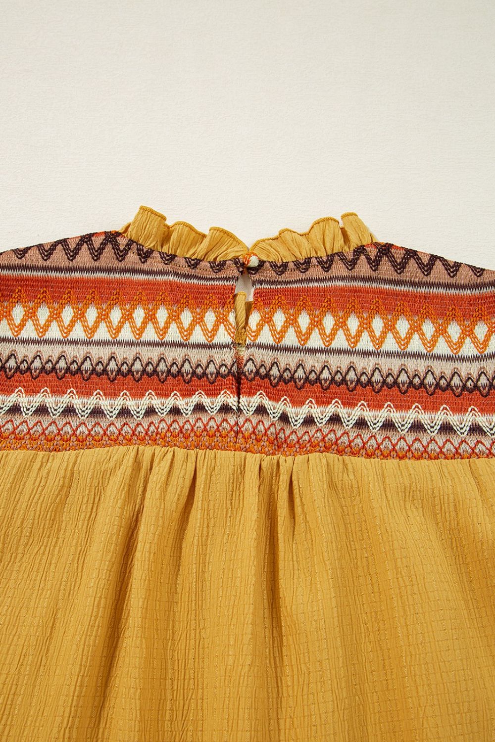 Mustard blouse with embroidered yoke and ruffled neckline detail.