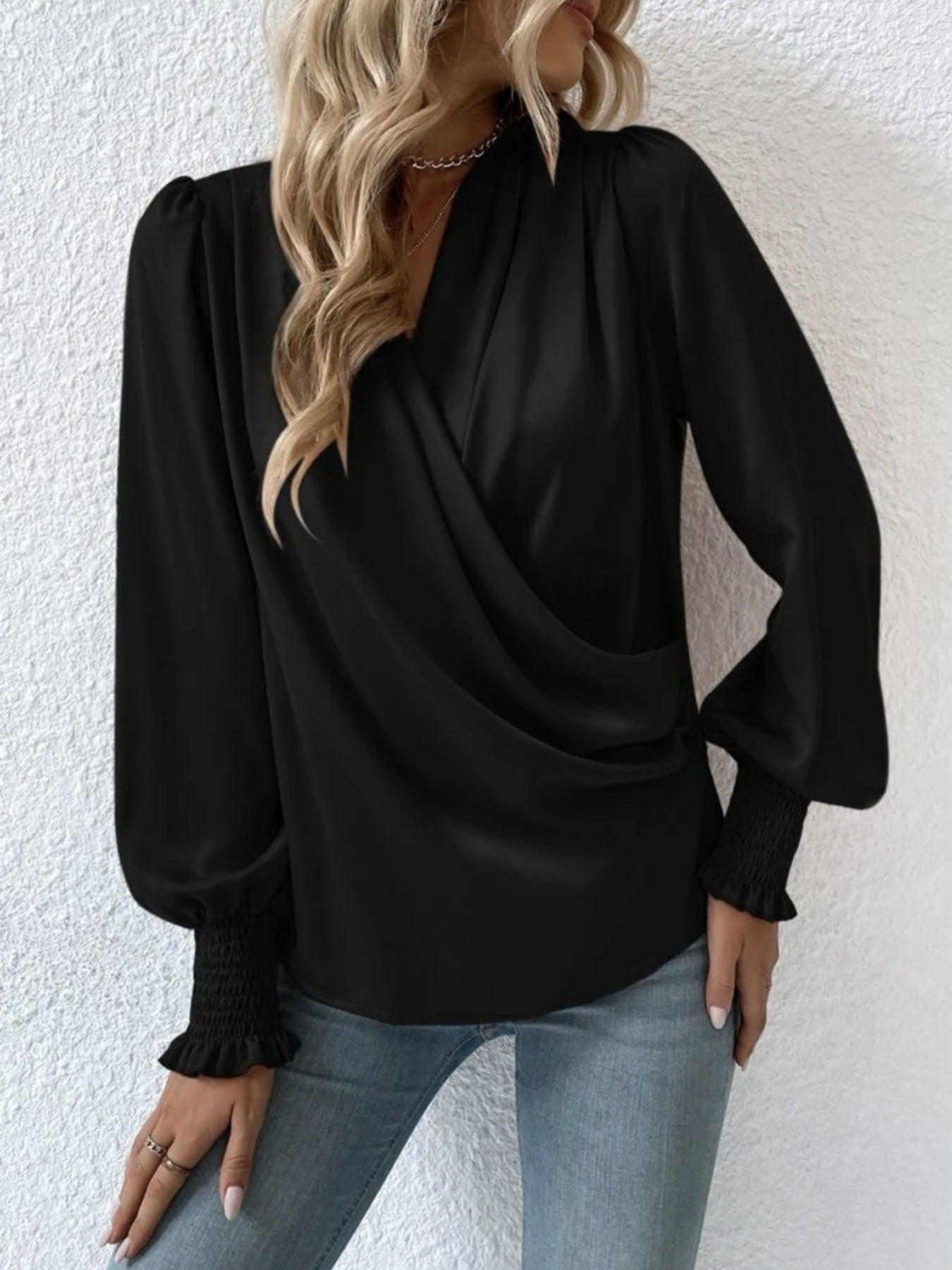 Black ruched surplice blouse with long puff sleeves and smocked cuffs.
