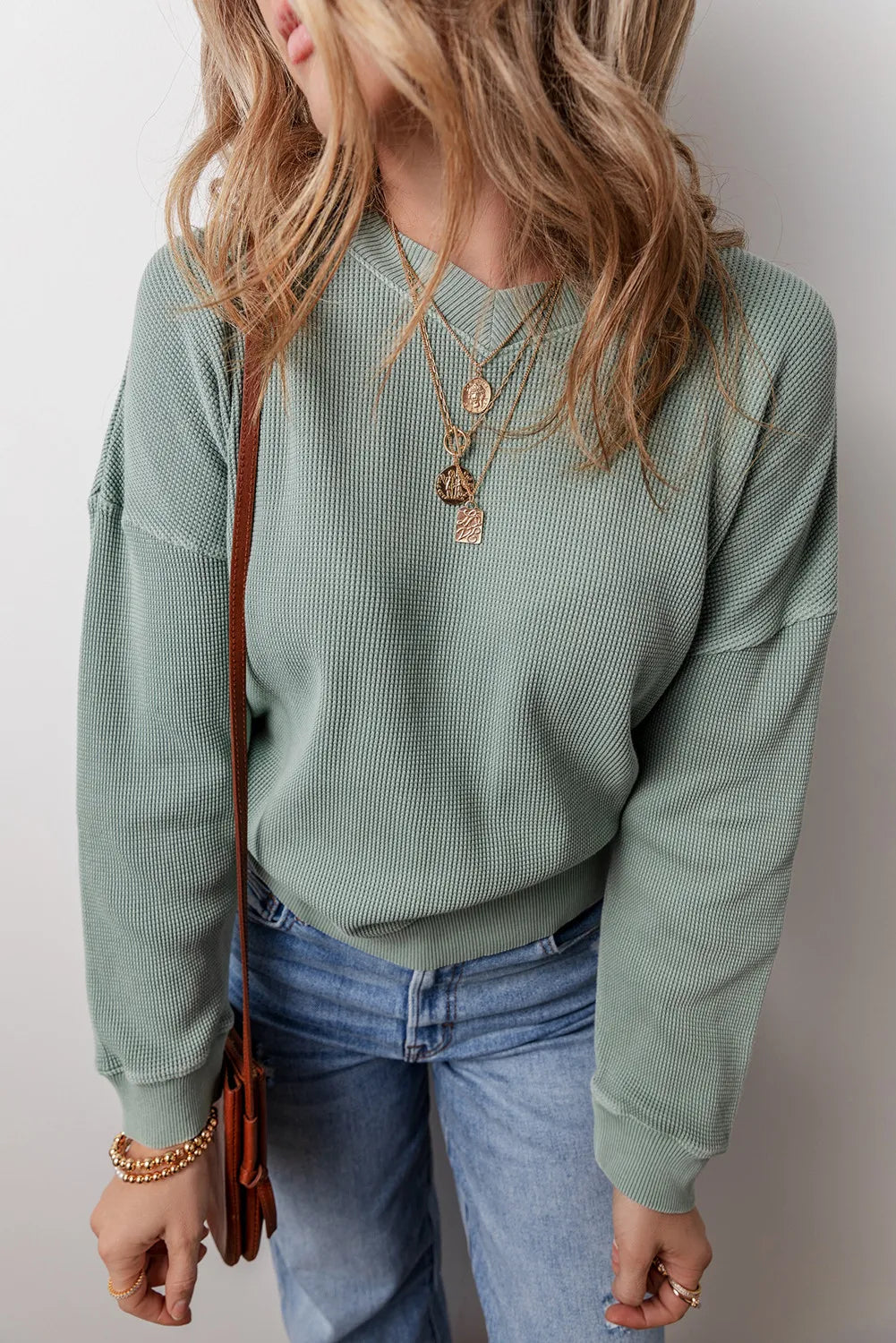 Sage waffle knit crewneck sweater with a relaxed fit, styled with jeans and layered necklaces.