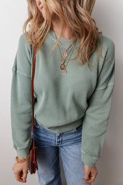 Sage waffle knit crewneck sweater with a relaxed fit, styled with jeans and layered necklaces.