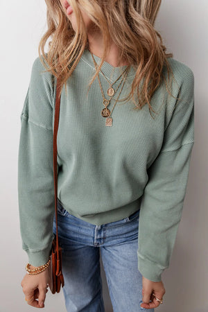 Sage waffle knit crewneck sweater with a relaxed fit, styled with jeans and layered necklaces.