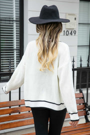 White acrylic cardigan with black trim detail on hem and cuffs