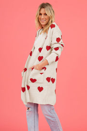 Cream longline knit cardigan with red heart motif and pockets.