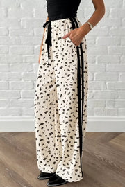 Maternity leggings in cream with abstract leopard print, drawstring waist, and black side stripes.