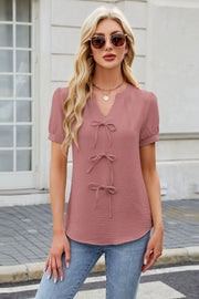 Dusty pink textured blouse with a V-neck and three bow-tie details.