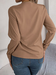 Camel V-neckline blouse with long sleeves and button cuffs, styled with jeans.
