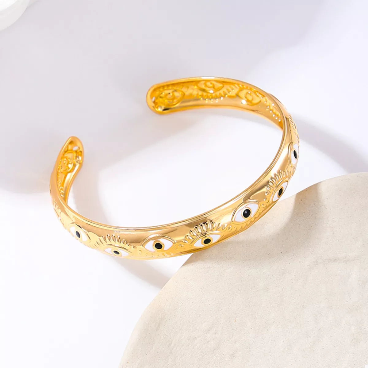 Golden evil eye bangle bracelet with 18K gold plating and intricate detailing.