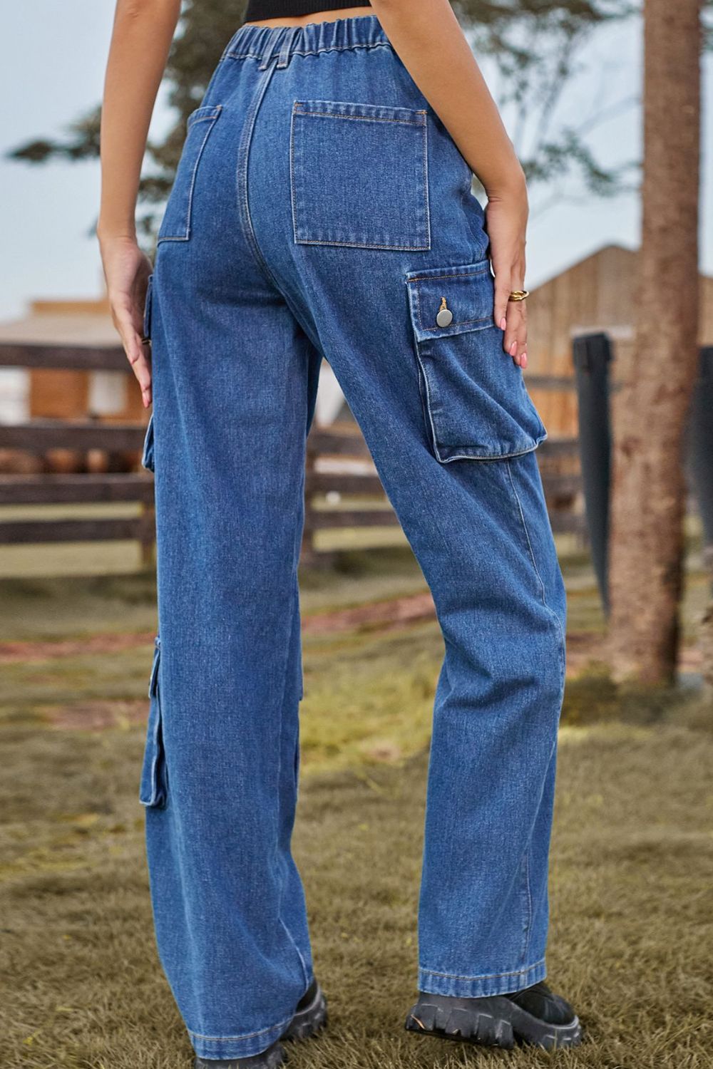 Relaxed wide leg denim cargo pants in medium blue with utility pockets and button details.