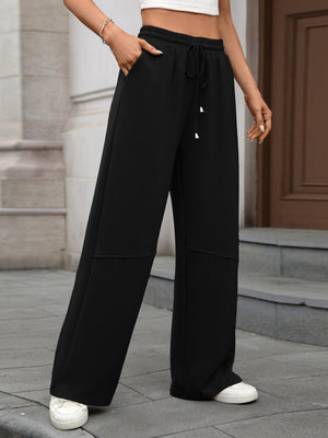 Black high-waist drawstring wide-leg pants with pockets and contrast stitching.