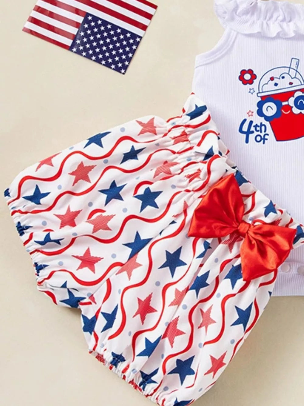Charming Patriotic baby set with star print bloomer shorts and a white bodysuit with patriotic graphic.