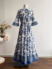 Maxi dress with blue floral print, V-neck, drawstring waist, tiered hem, and lace-trimmed bell sleeves.