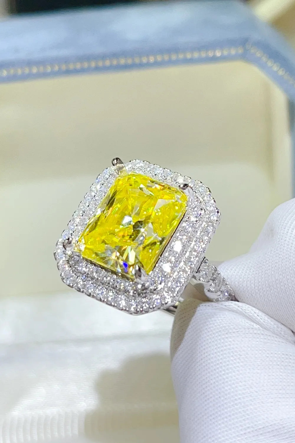 Radiant cut canary moissanite ring with diamond halo and intricate band.