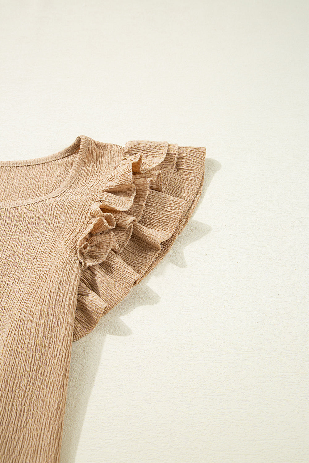 Tan textured blouse with ruffled cap sleeves and square neckline.