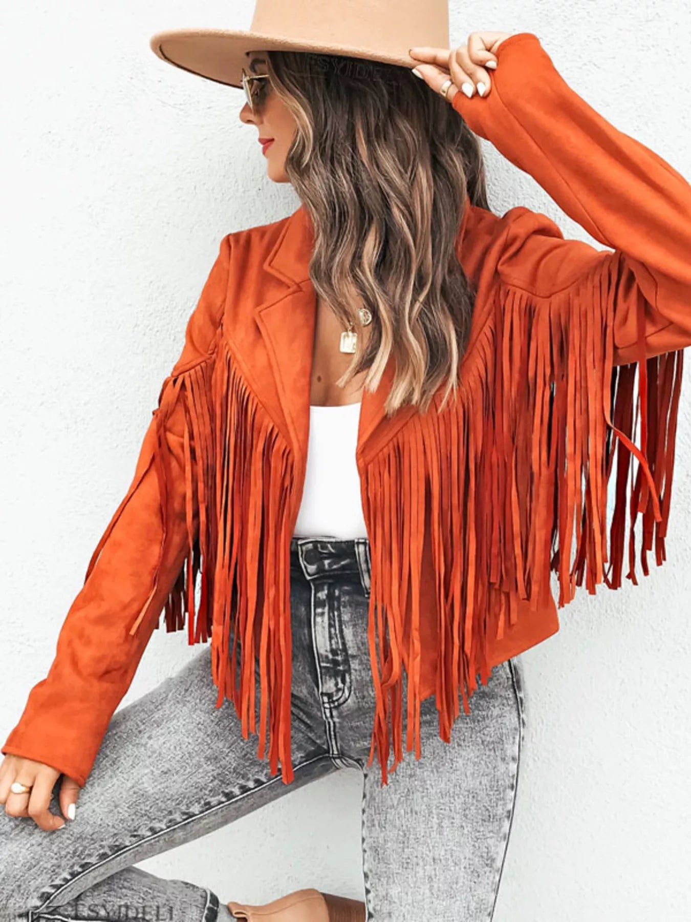 Orange fringe open front cropped jacket with lapels and long sleeves, styled with jeans.