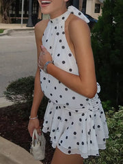 White polka dot halter neck mini dress with ruched waist and tiered skirt.