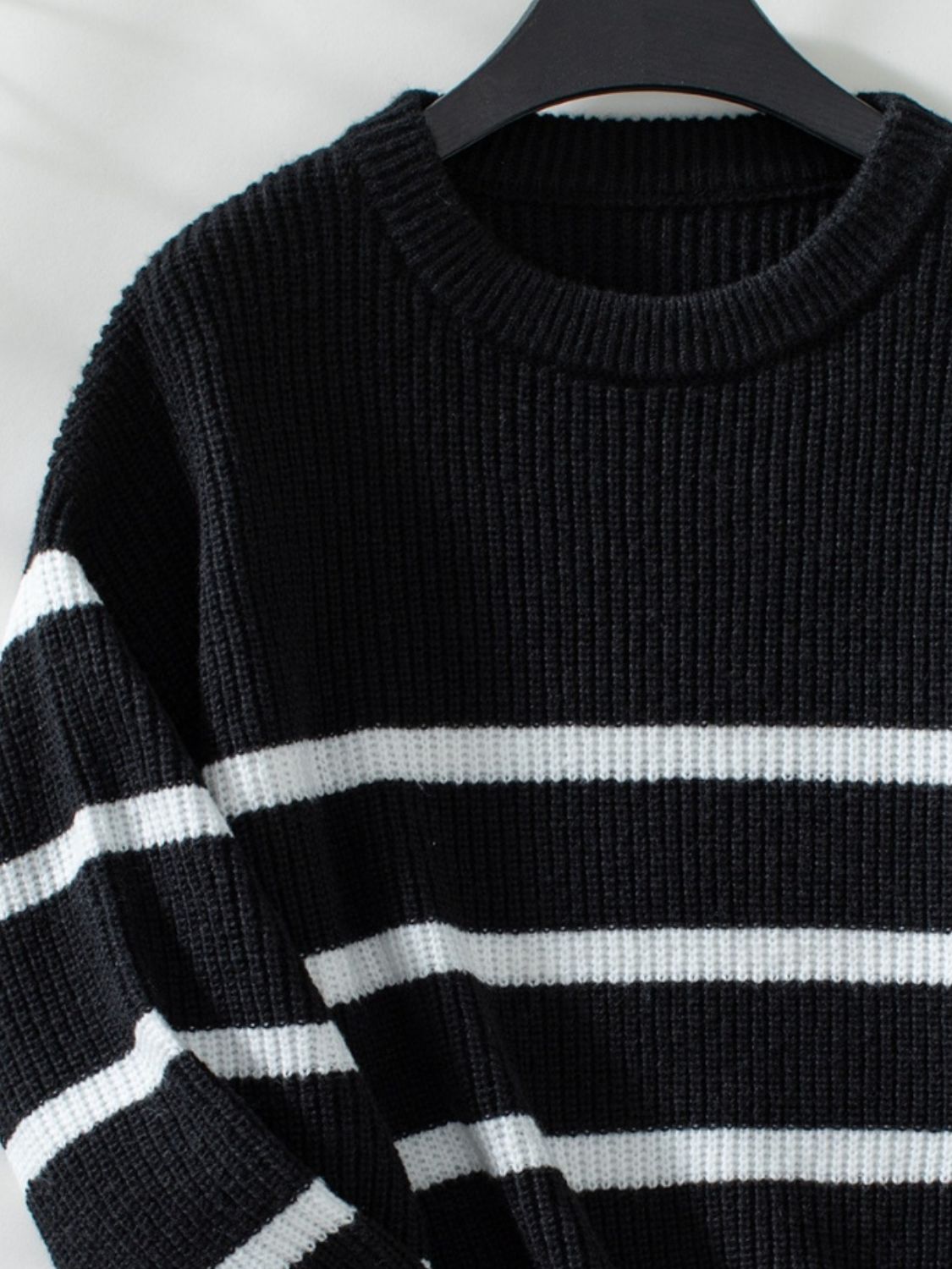 Black ribbed knit sweater with white horizontal stripes and crew neck.
