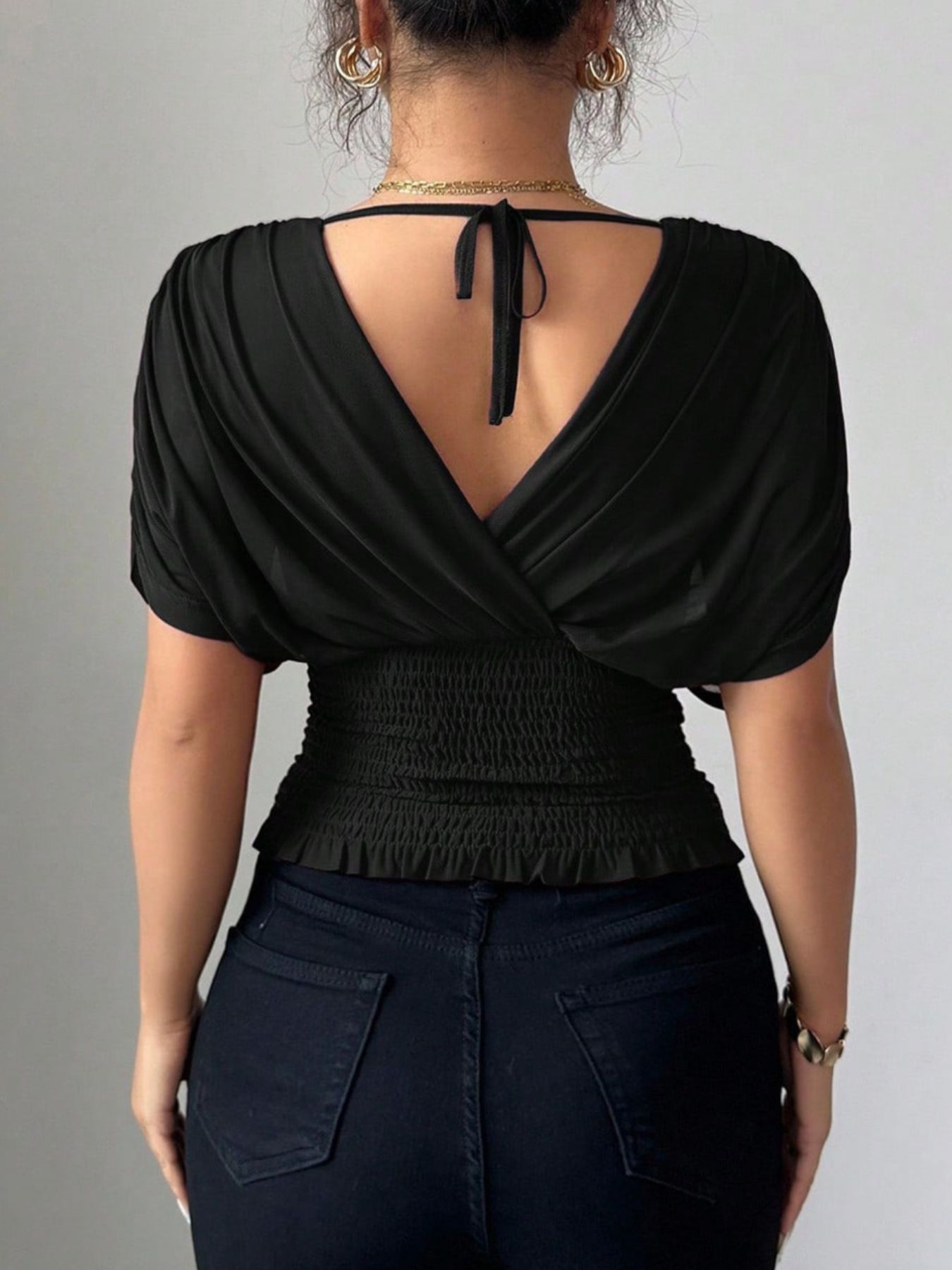 Black ruched surplice tunic with dolman sleeves and smocked waist detail.