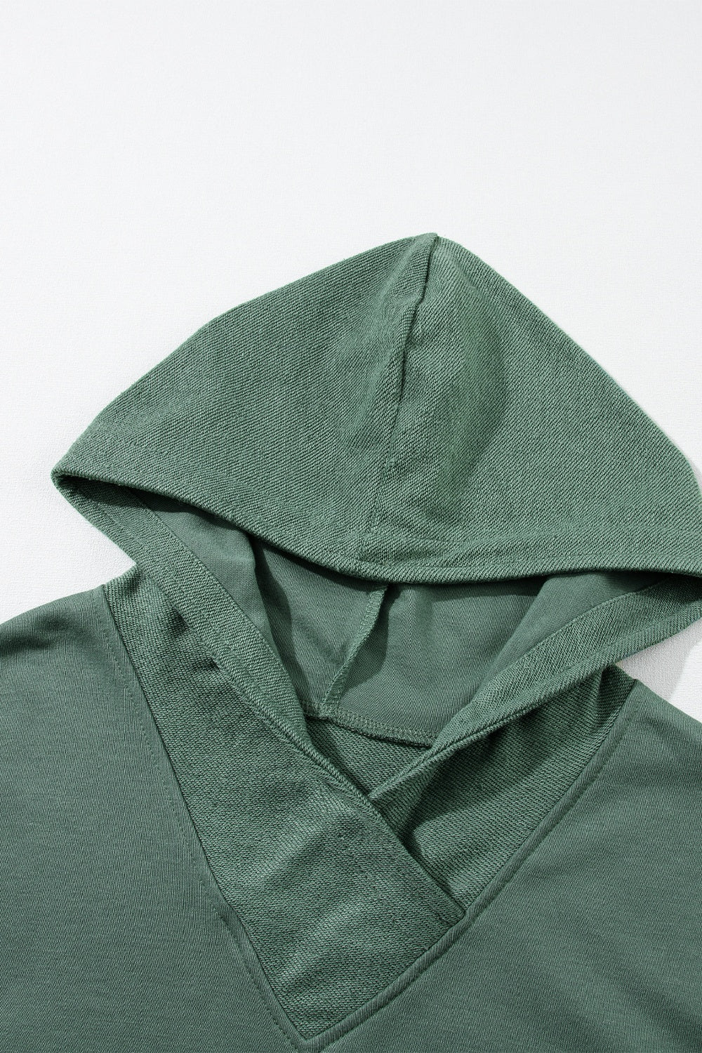 Sage green hoodie with textured V-neck detail and drawstring hood