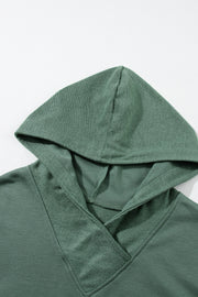 Sage green hoodie with textured V-neck detail and drawstring hood