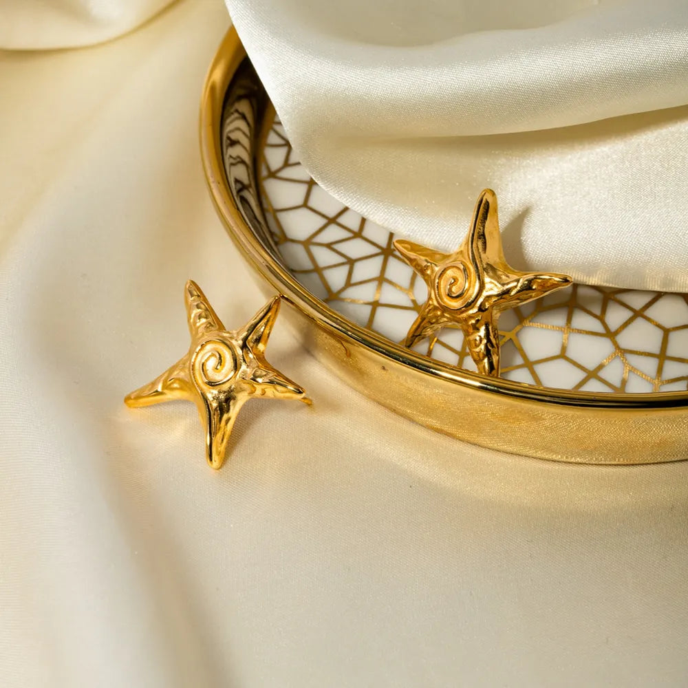 Golden starfish stud earrings with a spiral detail.