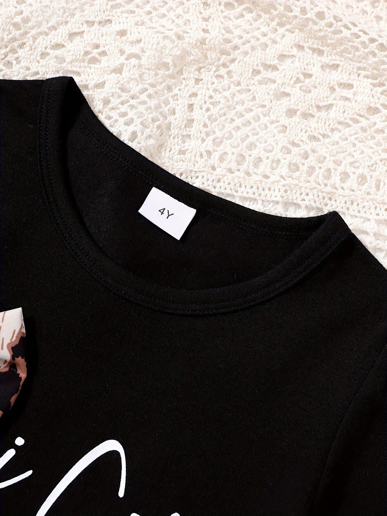 Black baby tee with leopard bow accent and white graphic print.