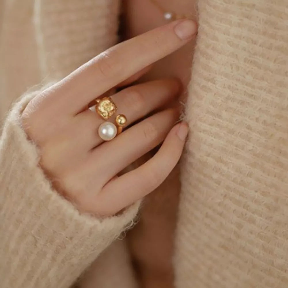 Lustrous pearl and gold open ring with textured detail.