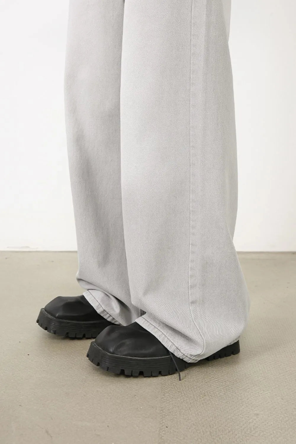 Bleached wash wide-leg denim trousers in gray, styled with chunky black boots.