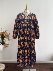 Maxi dress with V-neck, balloon sleeves, and floral print on navy blue fabric.