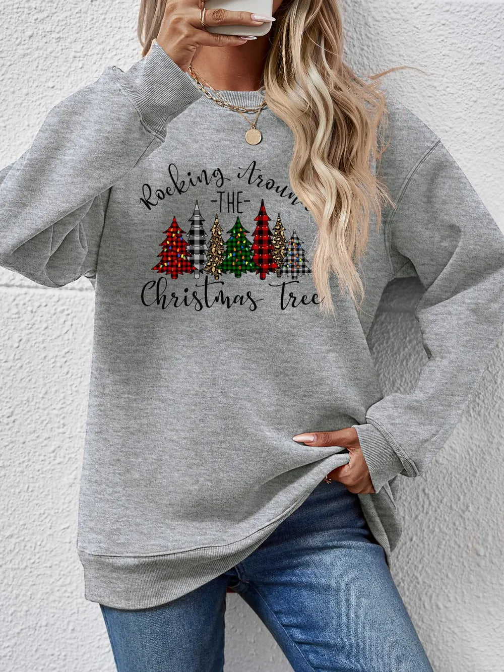 Gray crewneck sweatshirt with Christmas trees graphic and text.
