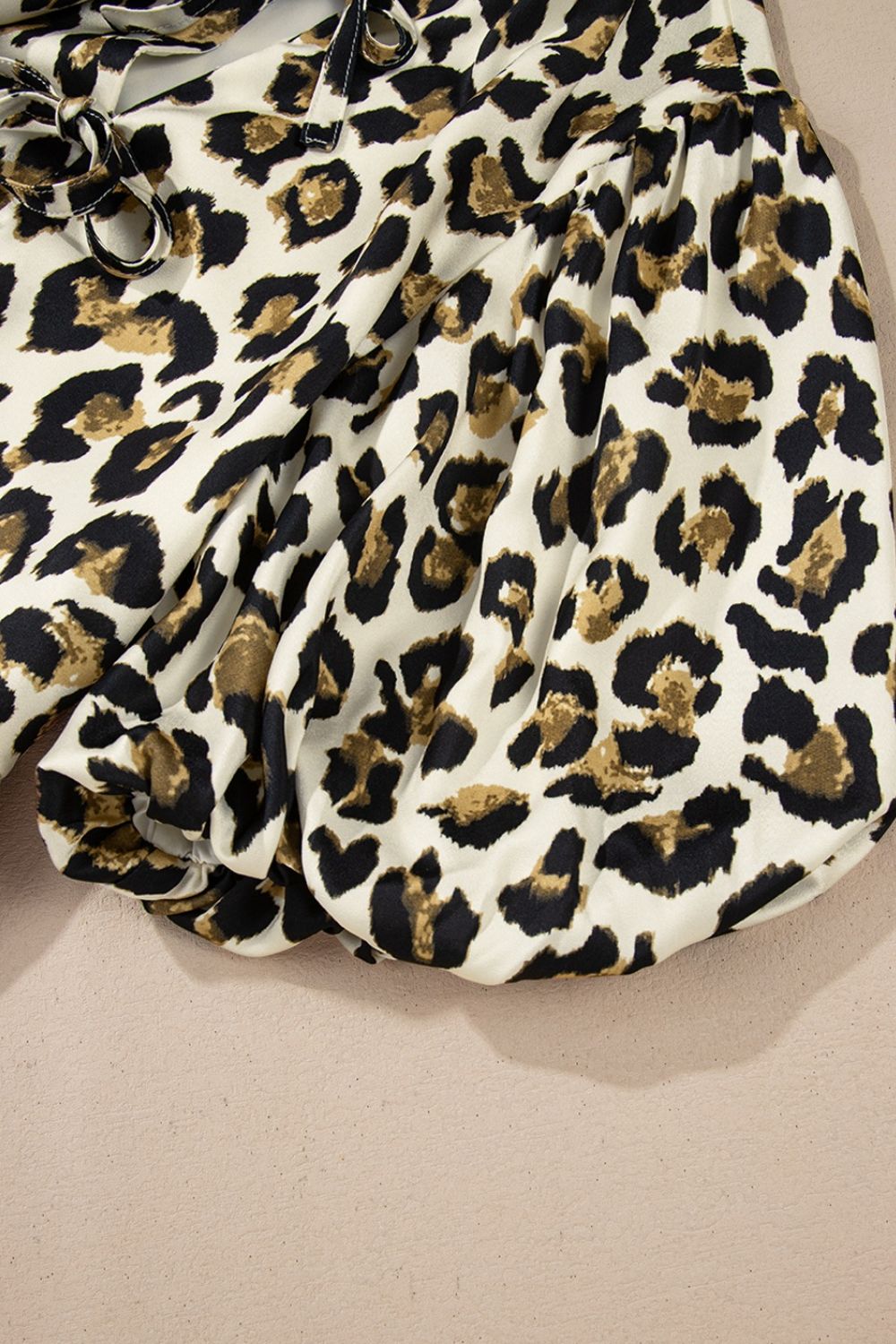 Leopard print tie-neck peplum blouse with gathered sleeves and cinched cuffs.