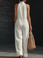 White halter neck wide-leg jumpsuit with pockets and cuffed hems.