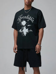 Black oversized tee with white "Moonlight" graphic of a person in a canoe under the moon.