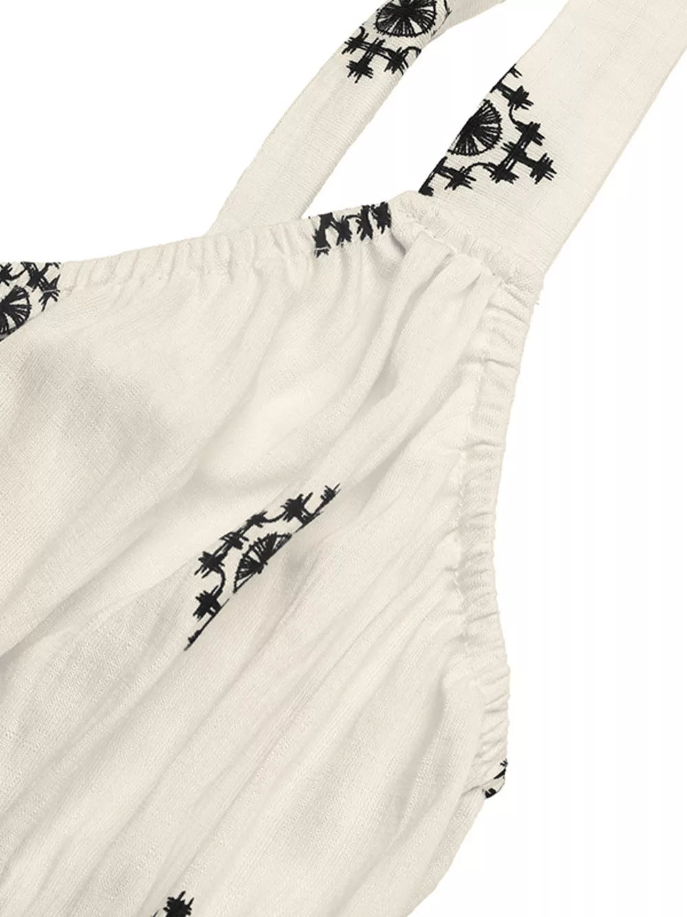 White midi dress with black geometric print, wide straps, and gathered detail.