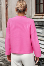 Pink ribbed mock neck sweater with volume sleeves and a cropped length.