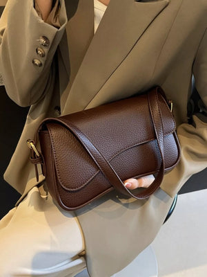 Sleek faux leather crossbody bag in coffee color with a curved flap closure.