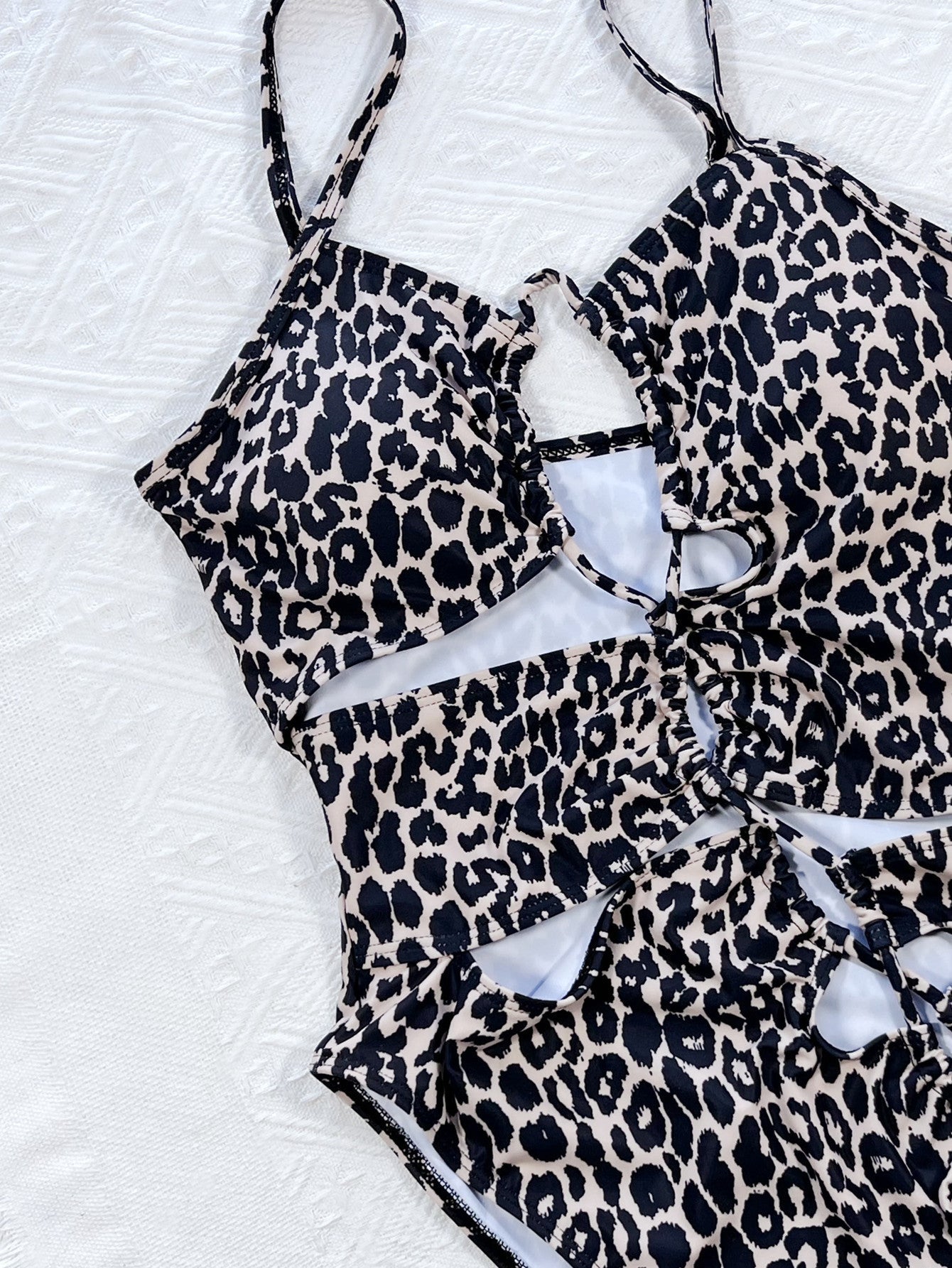 Leopard print one-piece swimsuit with cutout details and lace-up front.