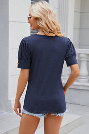 Dark blue tee with gathered short sleeves and gold button details.