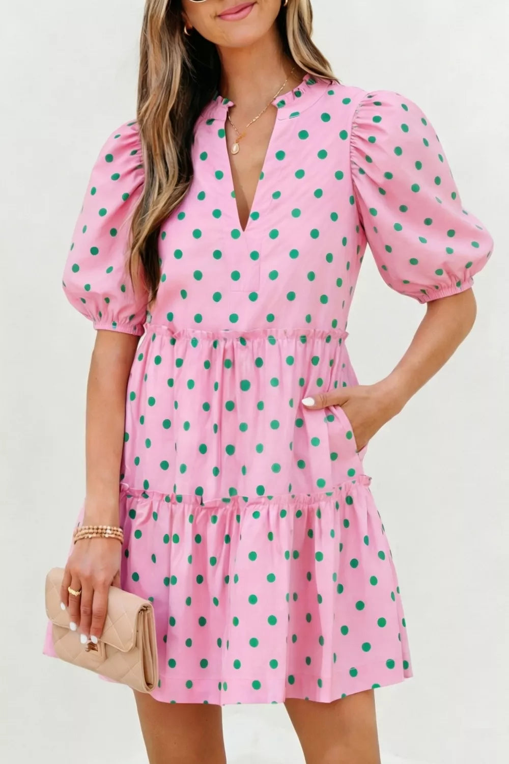 Pink polka dot tiered mini dress with puff sleeves and pockets.