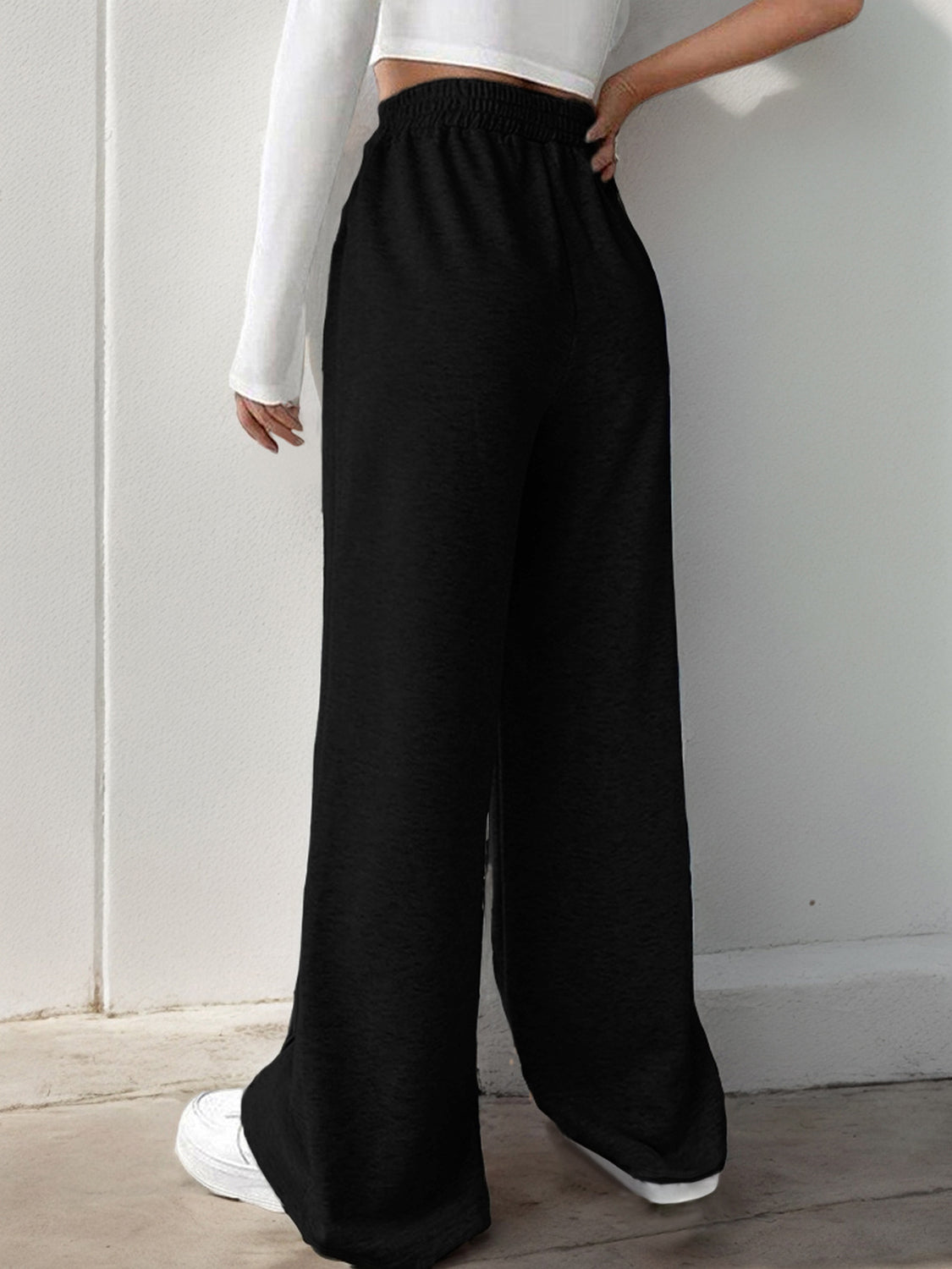 Black V-waistline palazzo sweatpants with center seams and wide legs.