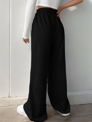 Black V-waistline palazzo sweatpants with center seams and wide legs.