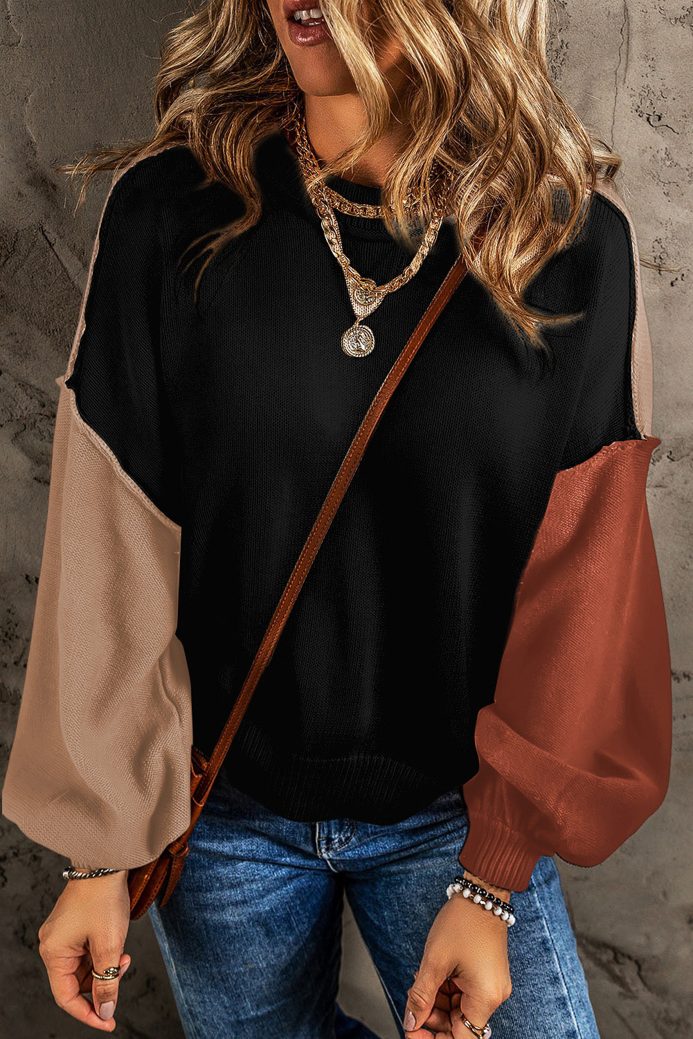 Sweater with black body and contrast balloon sleeves in tan and rust.