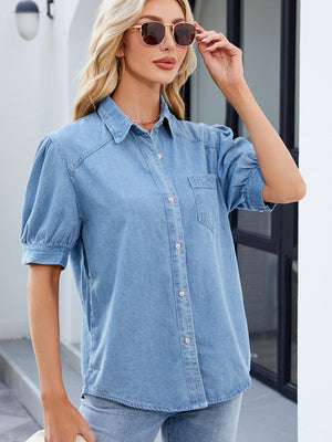 Medium wash denim button-down blouse with puffed short sleeves and a collared neckline.