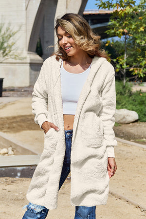 Cream plush hooded duster with pockets and thumbhole cuffs.