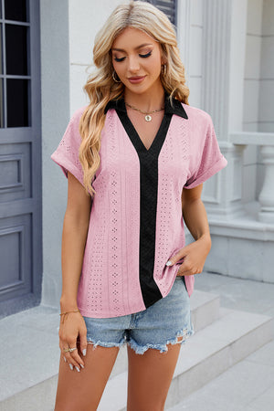Blush pink perforated polo top with black V-neck detail and short sleeves.