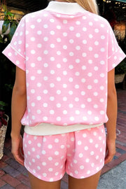 Pink polka dot top and shorts set with white trim, short sleeves, and cuffed hem.
