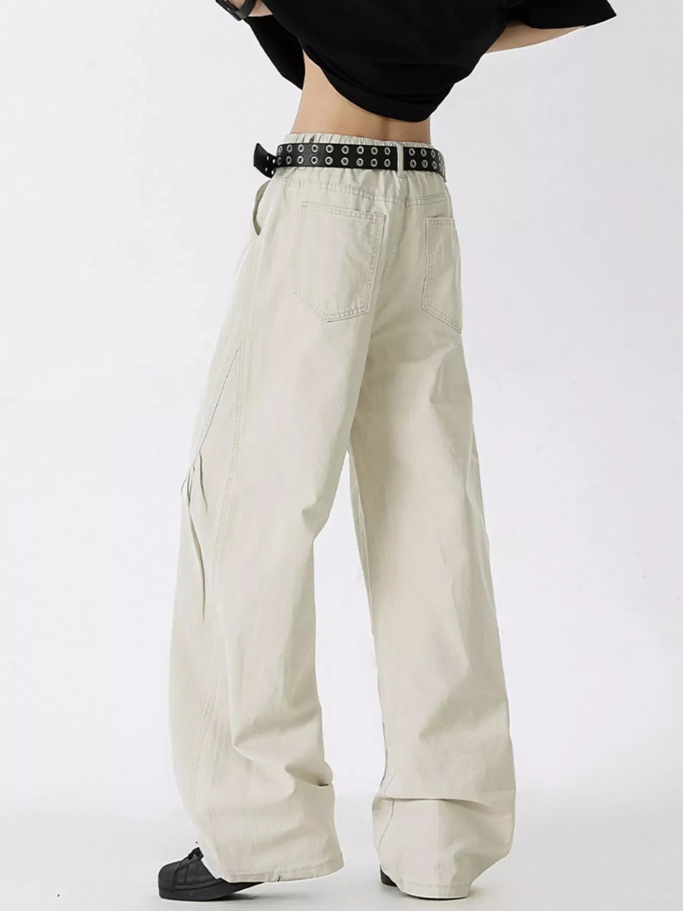 Men's oversized wide-leg jeans in off-white cotton with a black grommet belt.